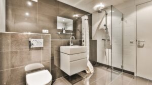 New bathroom design consisting of a floating toilet and sink, walk-in shower and tiled walls and floors