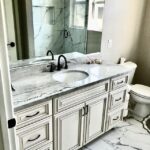 A bathroom with marble counter tops and a toilet.