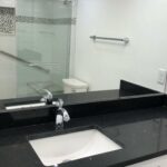 A bathroom featuring black granite countertops and a shower.