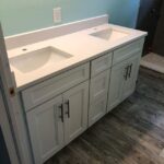 A white bathroom vanity with two sinks and a bathroom countertop.