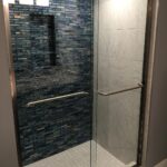 A bathroom featuring a shower with a glass door and blue tile, perfect for a bathroom remodel.