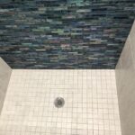 A tiled shower with a blue tiled wall, perfect for a bathroom remodel.
