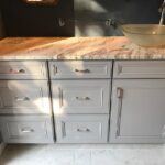 A bathroom remodel featuring gray cabinets and a marble sink.
