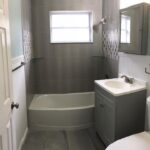A gray bathroom with a toilet, sink, and bathroom cabinet.
