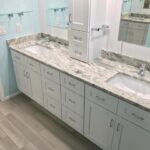 A bathroom with white cabinets and granite countertop.