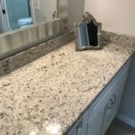 A bathroom with granite countertops and a mirror.