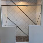 A modern bathroom design featuring a sleek glass shower door.