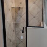 A glass door shower with a tiled floor.