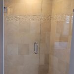 A bathroom with a glass shower door and beige tile, perfect for a bathroom remodel.