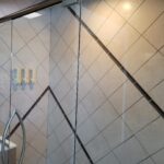 A bathroom with a glass shower door and tiled walls, perfect for a bathroom remodel.