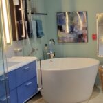 A bathroom with a white tub and blue cabinets, featuring a bathtub and bathroom cabinet.