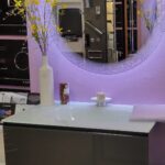 A bathroom with a purple mirror and a sink designed with a countertop.