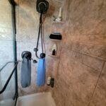 A tiled shower with a shower head and towels.