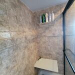 A bathroom with tiled walls and a shower stall, undergoing a bathroom remodel.