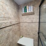 A bathroom with tiled walls and a shower stall.