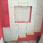 A bathroom is being remodeled with tile and red walls.