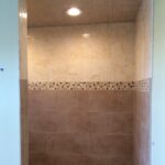 A bathroom with a tiled shower and tiled floor.