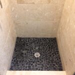 A shower with a black and white tiled floor.