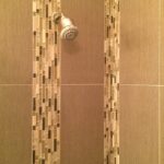 A shower head in a beige tile shower.