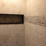 A beige tiled wall in a tiled shower.
