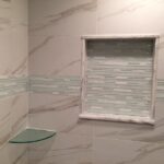 A tiled shower with a glass shelf, perfect for a bathroom remodel.