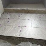 A bathroom remodel entails the installation of a tile floor.