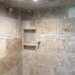 A tiled shower with beige tiles.