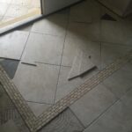 A bathroom countertop with a broken tile in the middle.
