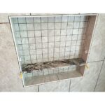A bathroom remodel featuring a tiled shower with a shelf integrated into the design.