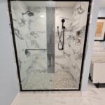 A bathroom with a glass shower door and marble floor, featuring a stylish bathroom remodel.