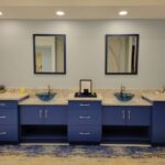 A bathroom with blue cabinets and mirrors.
