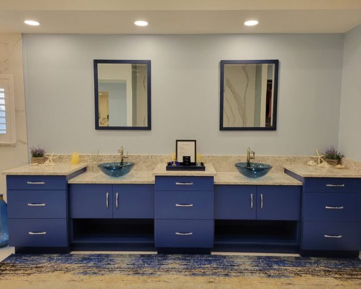 A bathroom with blue cabinets and mirrors, featuring a stylish bathroom design.