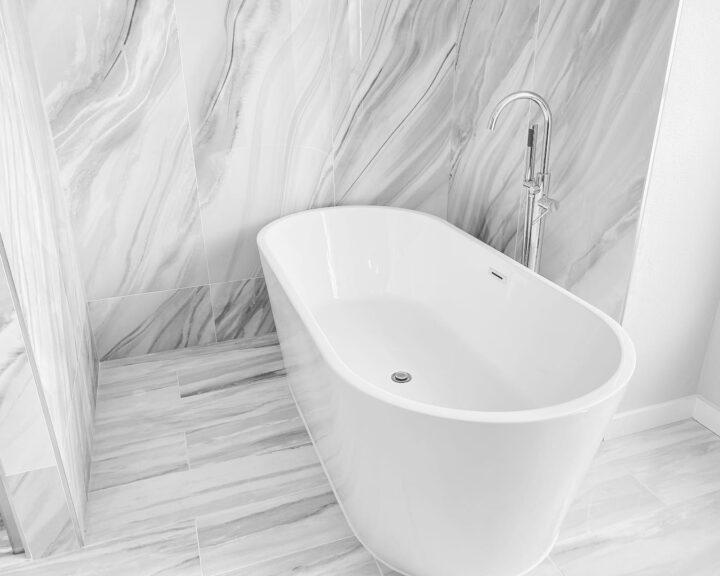 A black and white bathroom with a marble bathtub.