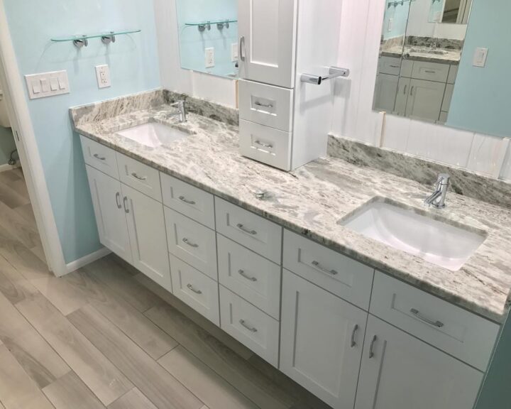 A bathroom with white cabinets and granite countertop.