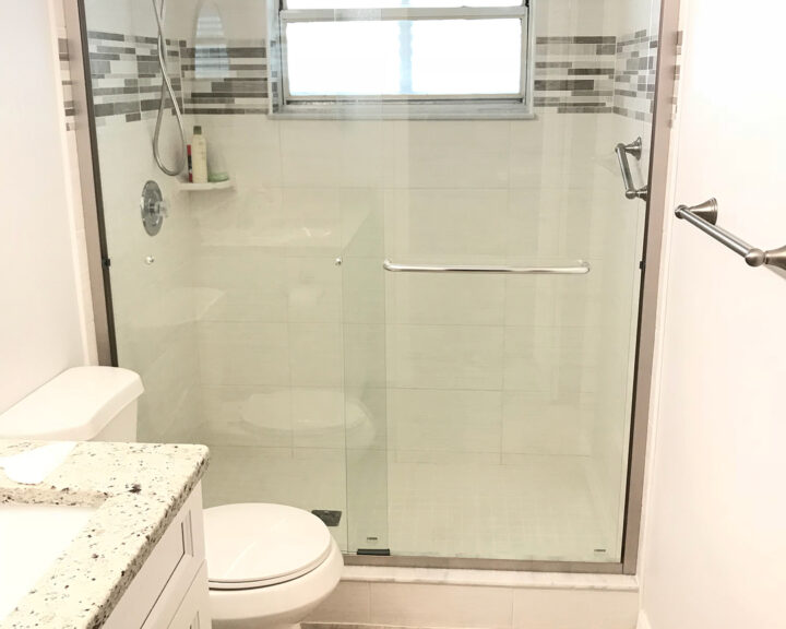 A white bathroom with a glass shower door featuring a sleek bathroom cabinet.