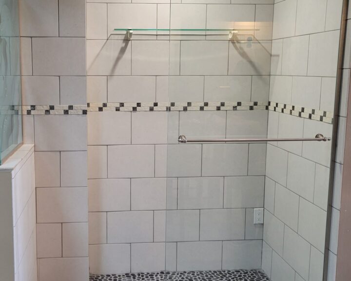 A bathroom with a glass shower door and tiled floor, showcasing a modern bathroom design.