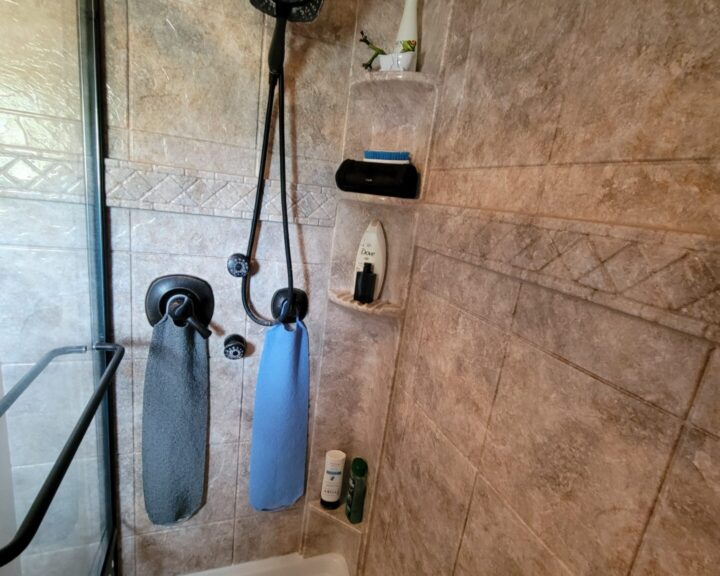 A tiled shower with a shower head and towels.