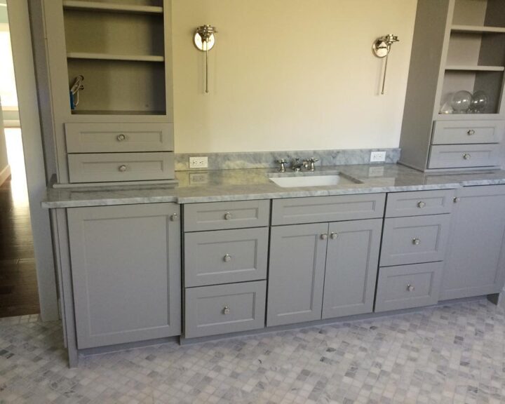 A bathroom with gray cabinets and marble counter tops, perfect for a bathroom remodel.