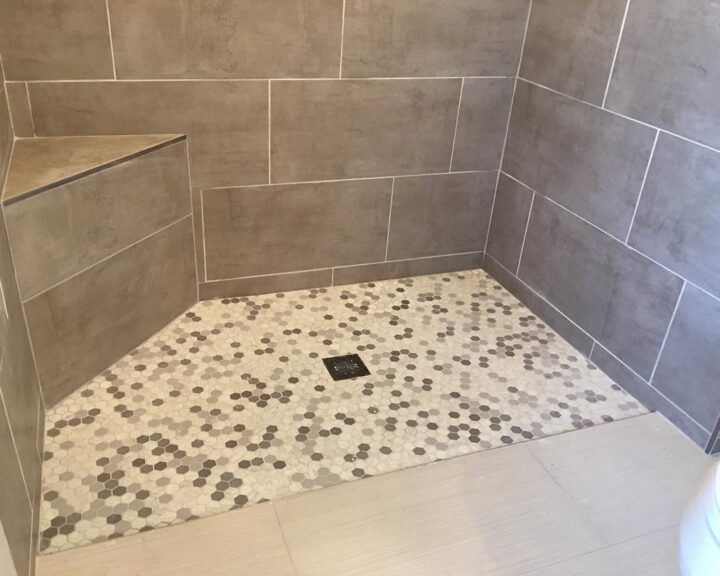 A beautifully remodeled bathroom featuring a tiled shower with an exquisite tiled floor design.