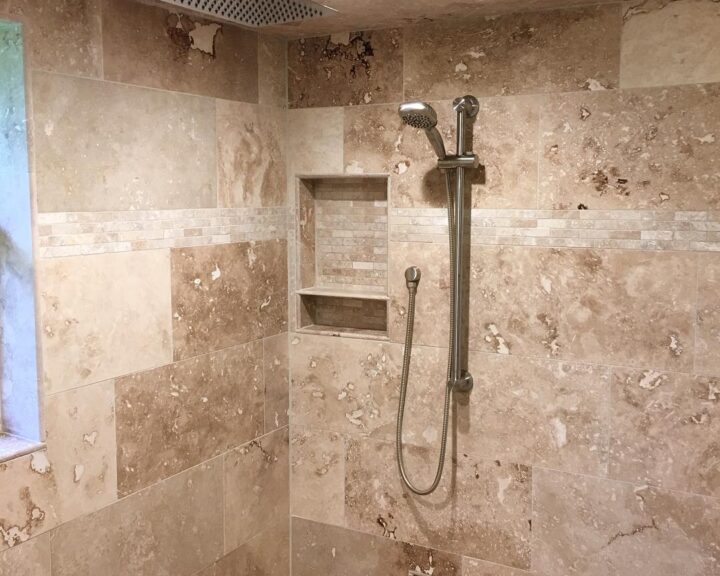 A tiled shower with a beige shower head.