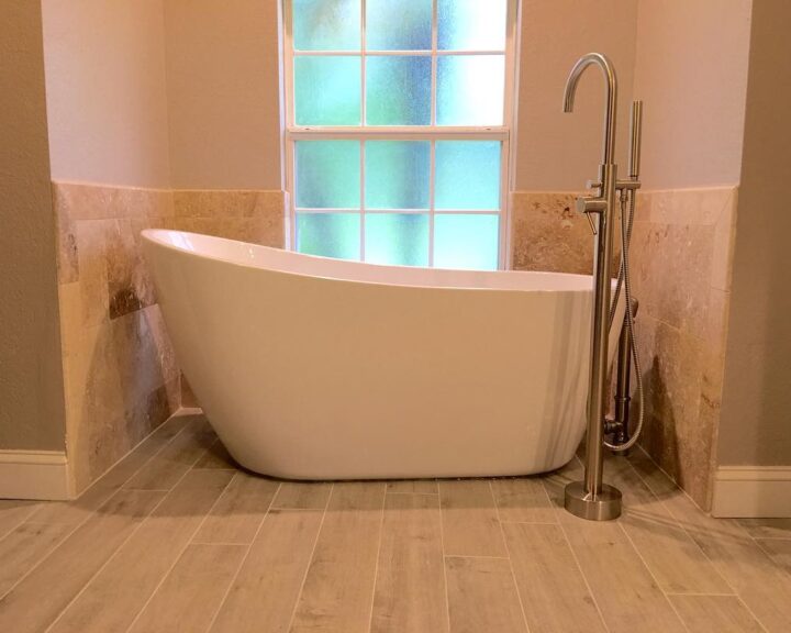 A sleek bathtub sits in front of a window, enhancing the ambiance of the bathroom design.