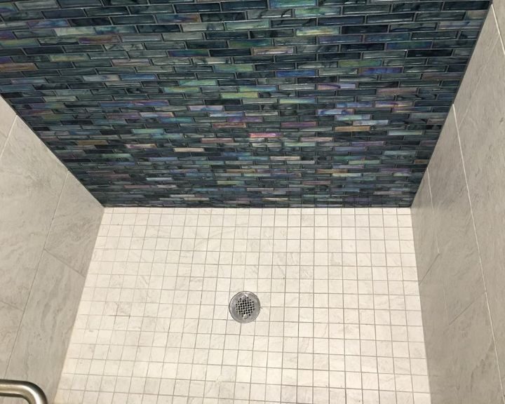 A blue tiled shower wall in a bathroom remodel.