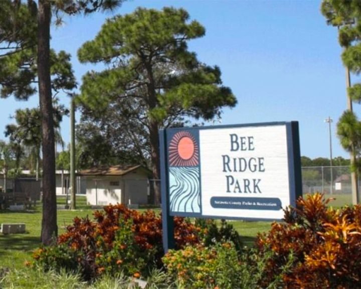 Bee ridge park sign in front of trees.