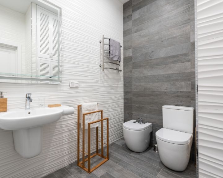 A modern bathroom featuring a white toilet and sink with an elegant bathroom design.