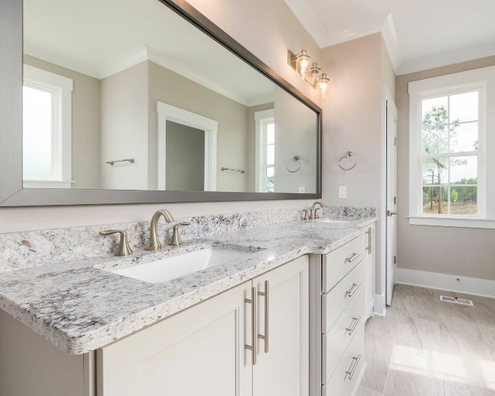 A bathroom remodel with granite counter tops and a large mirror.