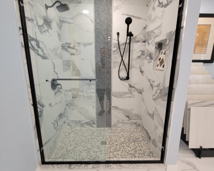 A bathroom with a glass shower door and marble floor, featuring a stylish bathroom remodel.